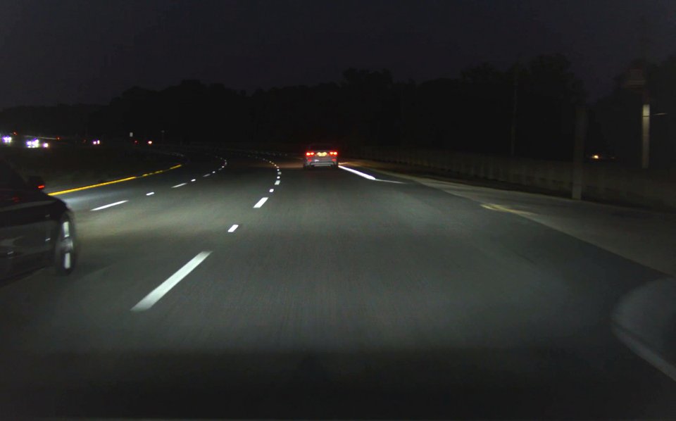 Night driving with only the headlight-lit stretch of lane line visible